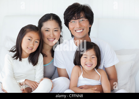 Tutta la famiglia felicemente seduta sul letto insieme Foto Stock