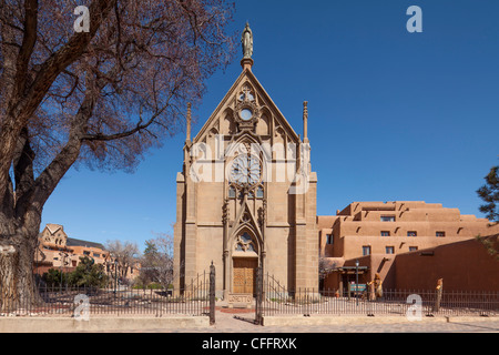 La storica Cappella di Loretto (Nostra Signora della Luce) a Santa Fe, Nuovo Messico, con la sua famosa facciata in stile neogotico accanto agli edifici in adobe Foto Stock
