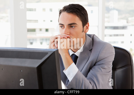 Imprenditore pensando davanti al suo computer Foto Stock