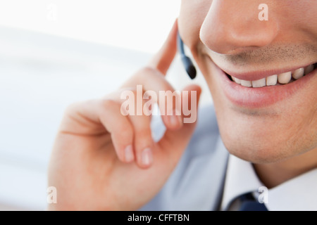 Close-up di un uomo sorridente la bocca parlando con una cuffia Foto Stock