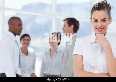 Tradeswoman sorridente in pensatori pongono con colleghi dietro di lei Foto Stock