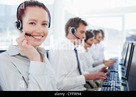 Sorridente agenti del call center con i suoi colleghi dietro di lei Foto Stock