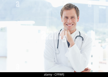 Medico sorridente in piedi accanto a una finestra Foto Stock