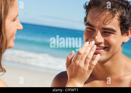 Donna mettendo alcuni sunscreen sul suo fidanzato del naso Foto Stock