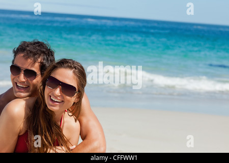 Coppia felice in spiaggia indossando occhiali da sole Foto Stock