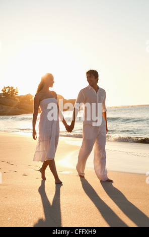 Coppia giovane di camminare sulla spiaggia al tramonto Foto Stock
