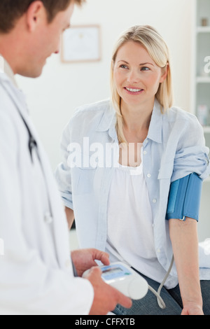 Donna sorridente ottenendo la sua pressione sanguigna misurata Foto Stock