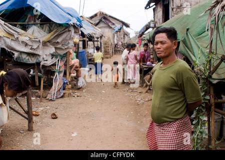 Il villaggio manager (a destra) è in piedi vicino alla sua casa in rovina in una povertà comunità colpite in Kampong Cham, Cambogia. Foto Stock