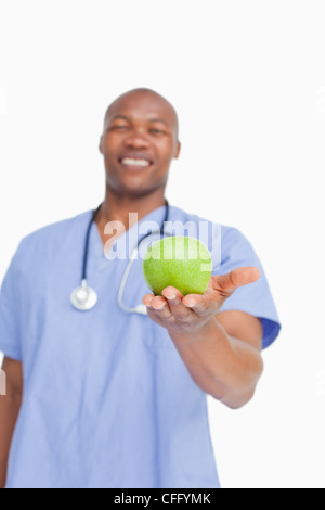 Sorridente medico tenendo premuto mela verde in mano Foto Stock
