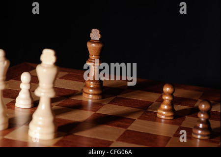 Chess endgame - re sotto pressione. Scena drammatica con lunghe ombre e sfondo nero. Foto Stock