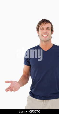 Uomo sorridente che guarda lontano mentre in piedi con la sua mano stesa Foto Stock