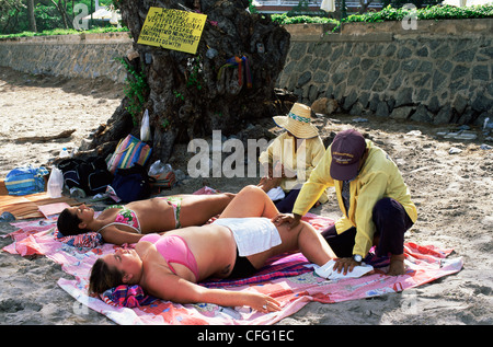 Thailandia, Hua Hin, turisti avente massaggi sulla spiaggia di Hua Hin Foto Stock