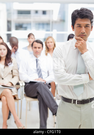 Imprenditore serio guardando avanti mantenendo il suo mento nelle sue mani Foto Stock