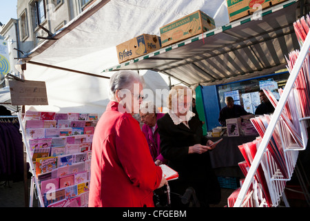 Le donne anziane esaminare biglietti di auguri su un mercato in stallo Loughborough, Inghilterra. Foto Stock