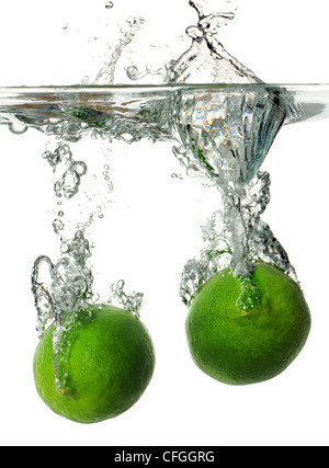 Limes schizzi in acqua su sfondo bianco Foto Stock