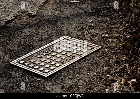 Copertura rete idrica in ghisa su strada asfaltata. Per il commercio dell'acqua, del mercato dell'acqua, dell'acqua come merce. Foto Stock