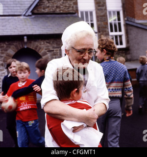 Una scuola cena lady comfort un ragazzo sconvolto in un villaggio scuola cantiere al tempo di giocare in Wales UK KATHY DEWITT Foto Stock