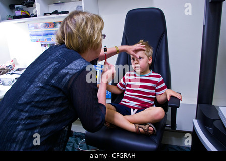 Un parco giochi per bambini all'ottico optometrista dà un piccolo ragazzo il suo primo esame dell'occhio. Foto Stock