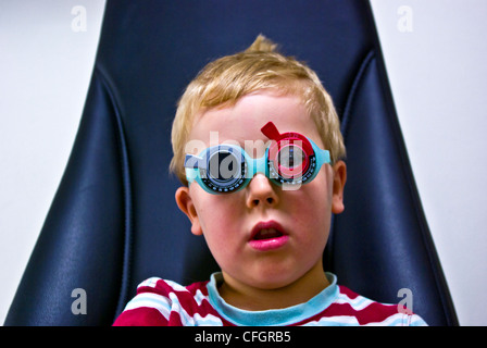 Un parco giochi per bambini all'ottico optometrista dà un piccolo ragazzo il suo primo esame dell'occhio. Foto Stock