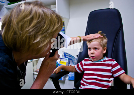 Un parco giochi per bambini all'ottico optometrista dà un piccolo ragazzo il suo primo esame dell'occhio. Foto Stock