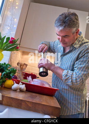 Uomo in cucina contemporanea stagionatura e preparare un pasto di pollo arrosto e verdure Foto Stock