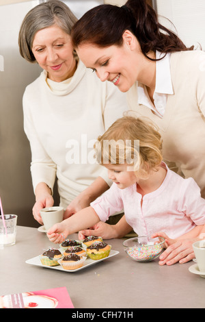 Madre e figlia come decorare le tortine spruzza felice insieme a casa Foto Stock