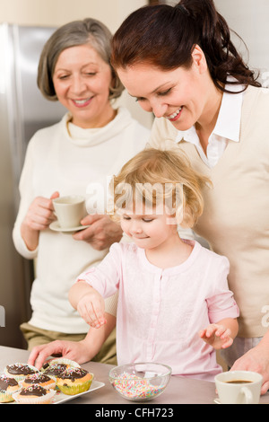 Madre e figlia come decorare le tortine spruzza felice insieme a casa Foto Stock