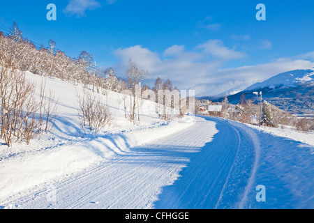 Coperta di neve su strada e fienili in villaggio norvegese di Laukslett, Troms, Nord della Norvegia, Europa Foto Stock
