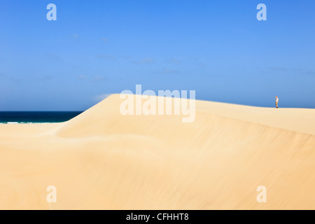 Spiaggia di sabbia con un uomo si trovava in cima ad una grande duna con sabbia che soffia nel vento. Praia de Chaves Boa Vista Isole di Capo Verde Foto Stock