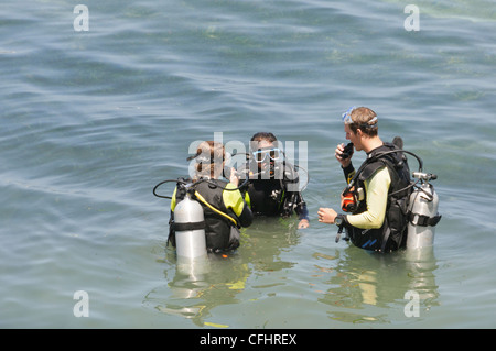 Open Water Scuba Instructor conducendo un corso di immersioni in acque confinate con due interracial studenti di sesso femminile Foto Stock