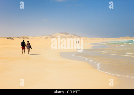 Le coppie passeggiando lungo la riva del tranquillo lunga spiaggia di sabbia bianca di Praia de Chaves, Rabil, Boa Vista, Isole di Capo Verde, Africa. Foto Stock