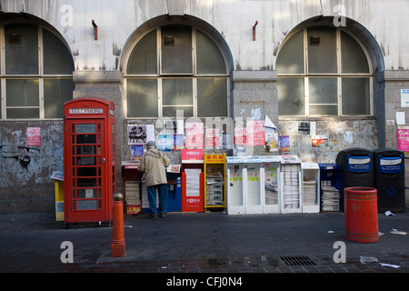 La gente di raccolta e libera lettura giornali cinesi da un edicola in Chinatown, Londra Foto Stock