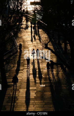 Ombre e sagome di pedoni camminando lungo la regina a piedi lungo il fiume Tamigi a South Bank di Londra, Regno Unito Foto Stock