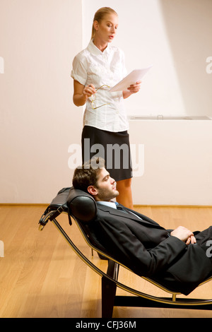 Lettura donna uomo disteso sulla chaise longue Foto Stock