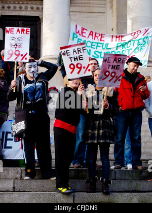 Occupare manifestanti in Portsmouth Guildhall square indossando Guy Fawkes maschere e portando cartelli che dichiara "ci sono il 99%' Foto Stock