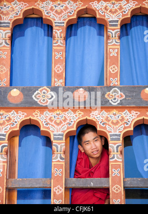 Giovane monaco buddista guardando fuori da una finestra a Trongsa Dzong, Trongsa, Bhutan, Asia Foto Stock