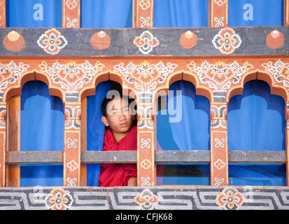 Giovane monaco buddista guardando fuori da una finestra a Trongsa Dzong, Trongsa, Bhutan, Asia Foto Stock