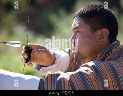 Uomo locale di prendere parte al concorso di tiro con l'arco usando il tradizionale arco, Jakar, Bumthang, Bhutan, Asia Foto Stock