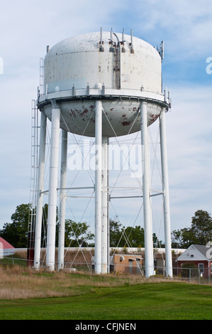 Torre d'acqua bianca situata in campagna sotto un cielo blu, Nord America, Stati Uniti. Grande serbatoio rialzato per la conservazione dell'acqua su supporti in acciaio. Foto Stock
