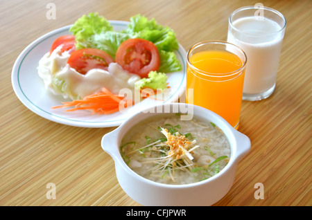 In stile asiatico zuppa di riso con erbe aromatiche in una ciotola , insalata fresca e latte , succo di arancia Foto Stock