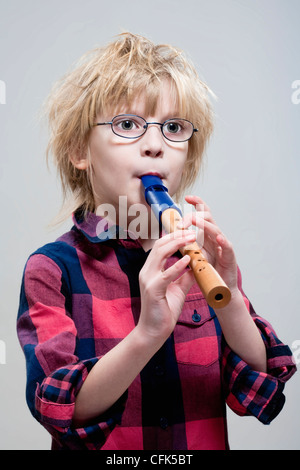 Ragazzo con gli occhiali a giocare il suo flauto - isolato su grigio Foto Stock