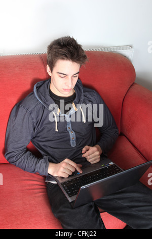 Giovane maschio seduto da solo utilizzando un computer portatile.