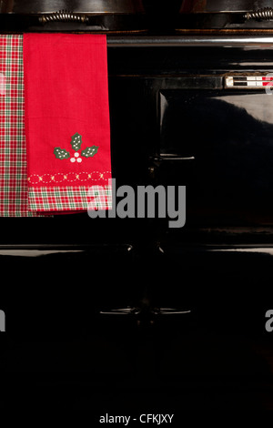 Holly motif asciugamano appeso alla rotaia di un Aga piano di cottura Foto Stock