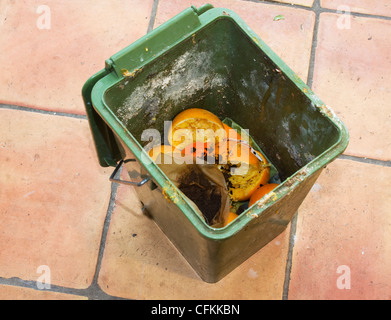 Un compost di sporco della benna riempita con bucce di arancia e filtri per caffè, sul pavimento della cucina Foto Stock