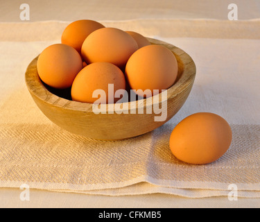 6 marrone uova di pollo in una ciotola di legno sulla trama panno di lino. Foto Stock