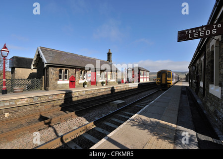 A nord del convoglio ferroviario avvicinando Garsdale stazione, Carlisle per estinguere la linea ferroviaria, Yorkshire Dales, Inghilterra Foto Stock