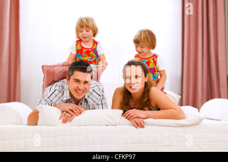Due gemelli sorridente figlie seduti sulle spalle dei genitori Foto Stock