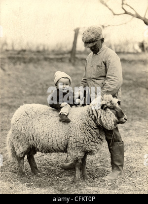 Nonno aiutando nipote di cavalcare una pecora Foto Stock