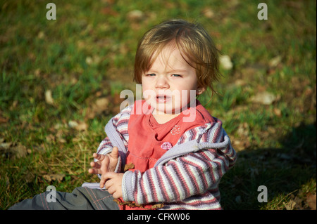 Poco piangere ragazza seduta sull'erba Foto Stock