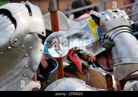 L'Italia, Lombardia, rievocazione storica, l'uomo in tuta di Armor Acqua Potabile da una bottiglia Foto Stock